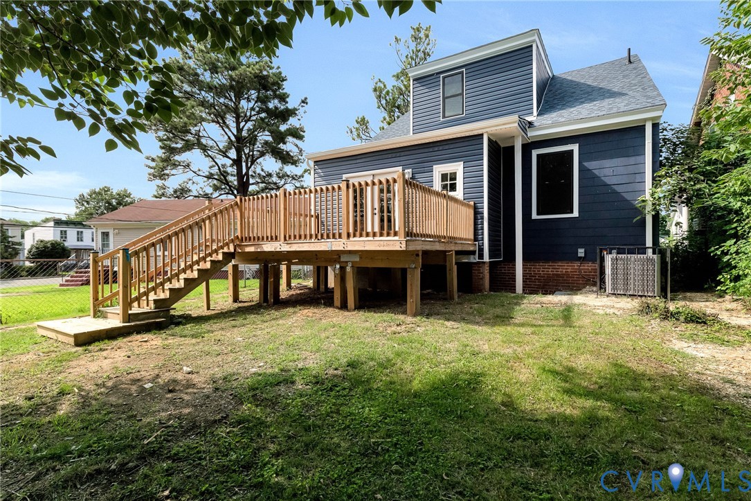 Rear exterior featuring blue siding, a wooden deck with railing, and a ground-level concrete step