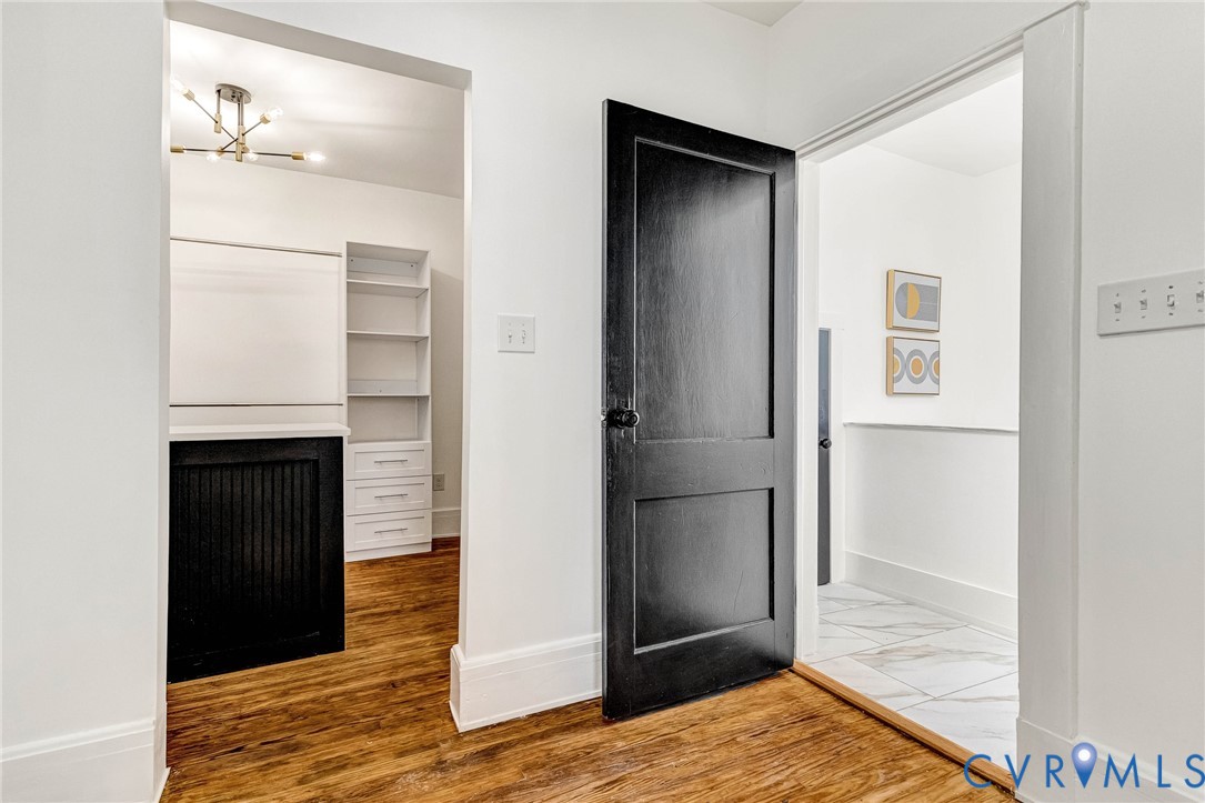 Wood-finish flooring, a contemporary ceiling light fixture, built-in shelving, and built-in drawers