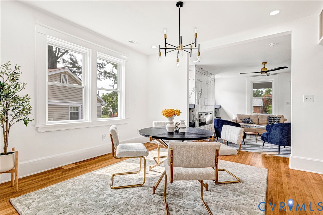 Hardwood flooring throughout, modern chandelier, recessed lighting, and a contemporary fireplace with a marble-finish surround