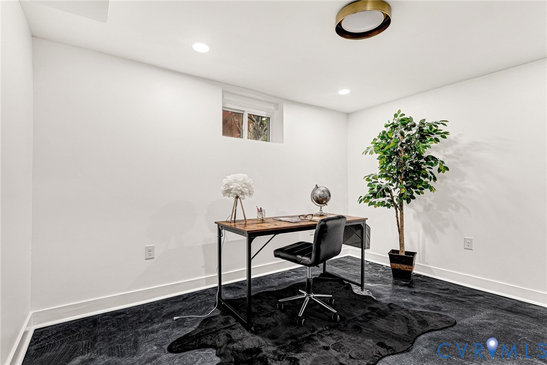 White walls with a single window, recessed lighting, and a modern brass-finish ceiling fixture