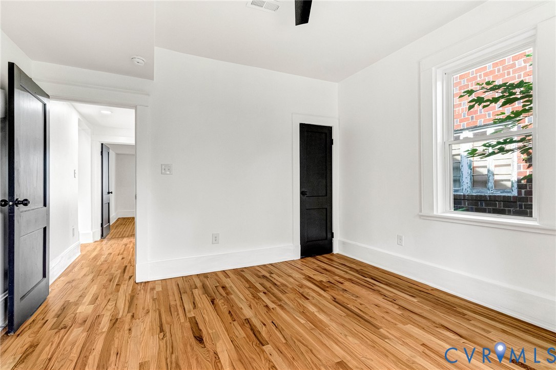 Hardwood flooring, painted interior doors, white trim, and a white window frame
