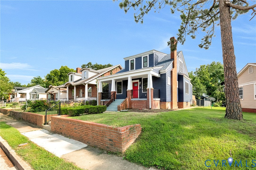 Crafted with a prominent brick chimney, this residence features a deep blue exterior and a welcoming front porch with white columns