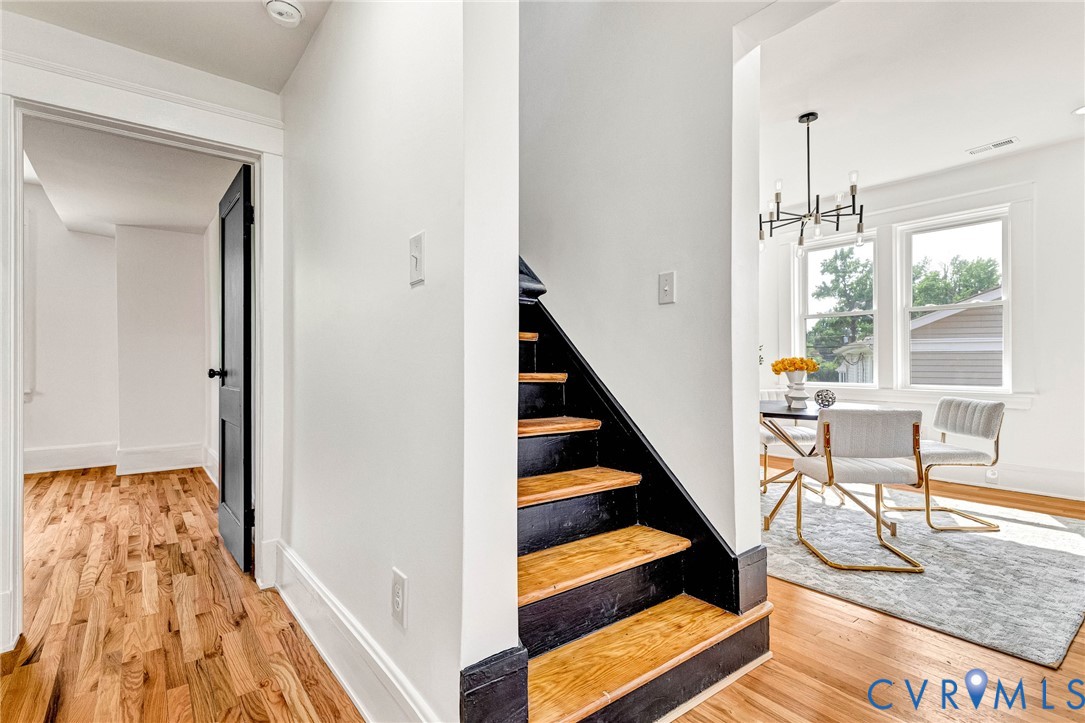 Hardwood flooring throughout, modern black interior doors, contemporary lighting fixture, and a built-in staircase