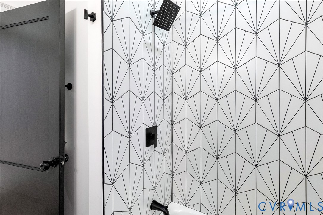 Shower featuring geometric tile, a matte black shower head, and coordinating matte black fixtures