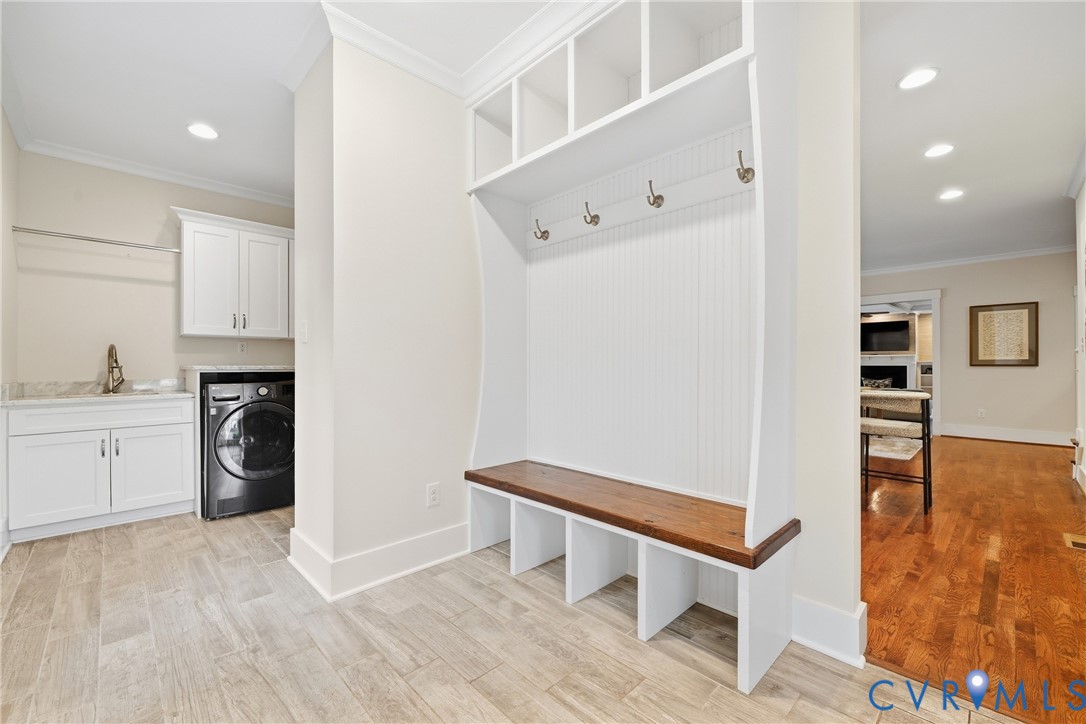 Laundry area featuring a utility sink with a tall faucet, white cabinetry, and wood-finish flooring
