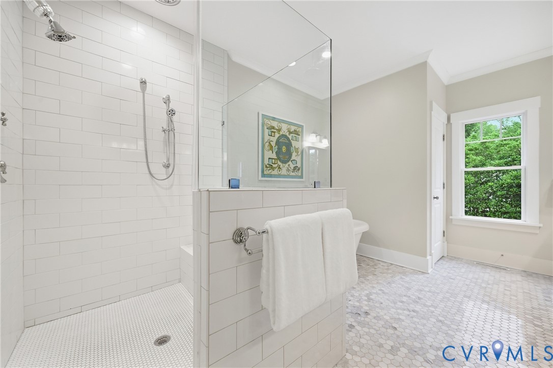 Spacious shower with subway tile surround, glass enclosure, and a built-in bench