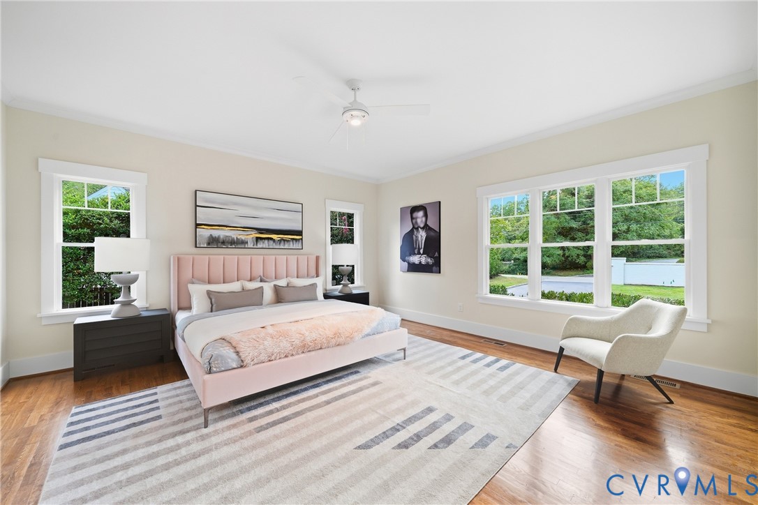 Hardwood flooring throughout, multiple windows, ceiling fan with integrated lighting, and crown molding