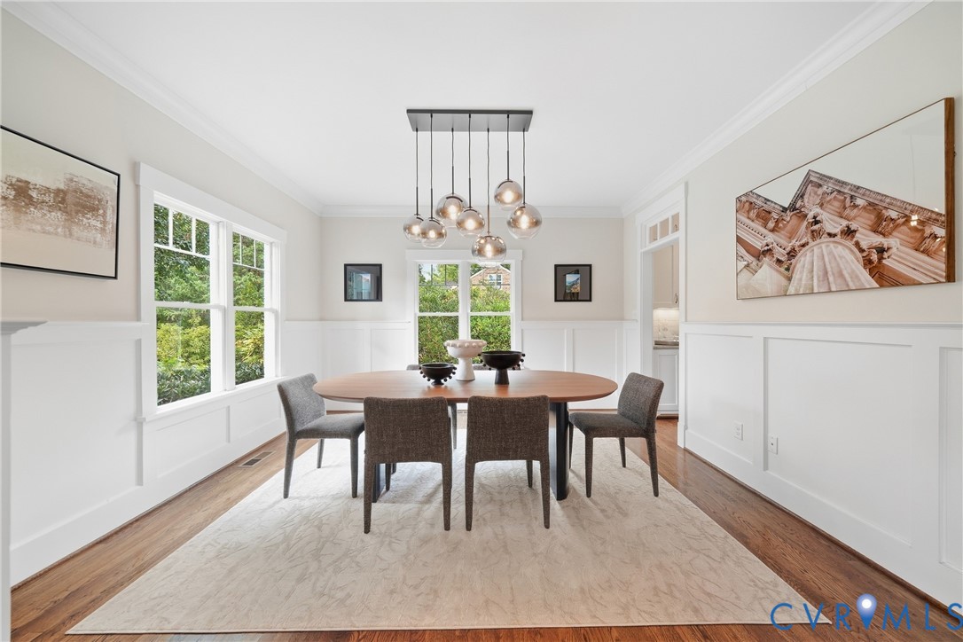 Hardwood flooring, wainscoting, crown molding, double-hung windows, and a multi-pendant light fixture
