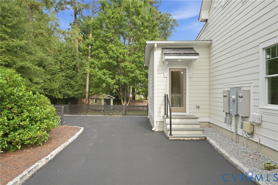 Paved driveway with granite curbing, leading to a side entry with stone steps and a wrought iron railing