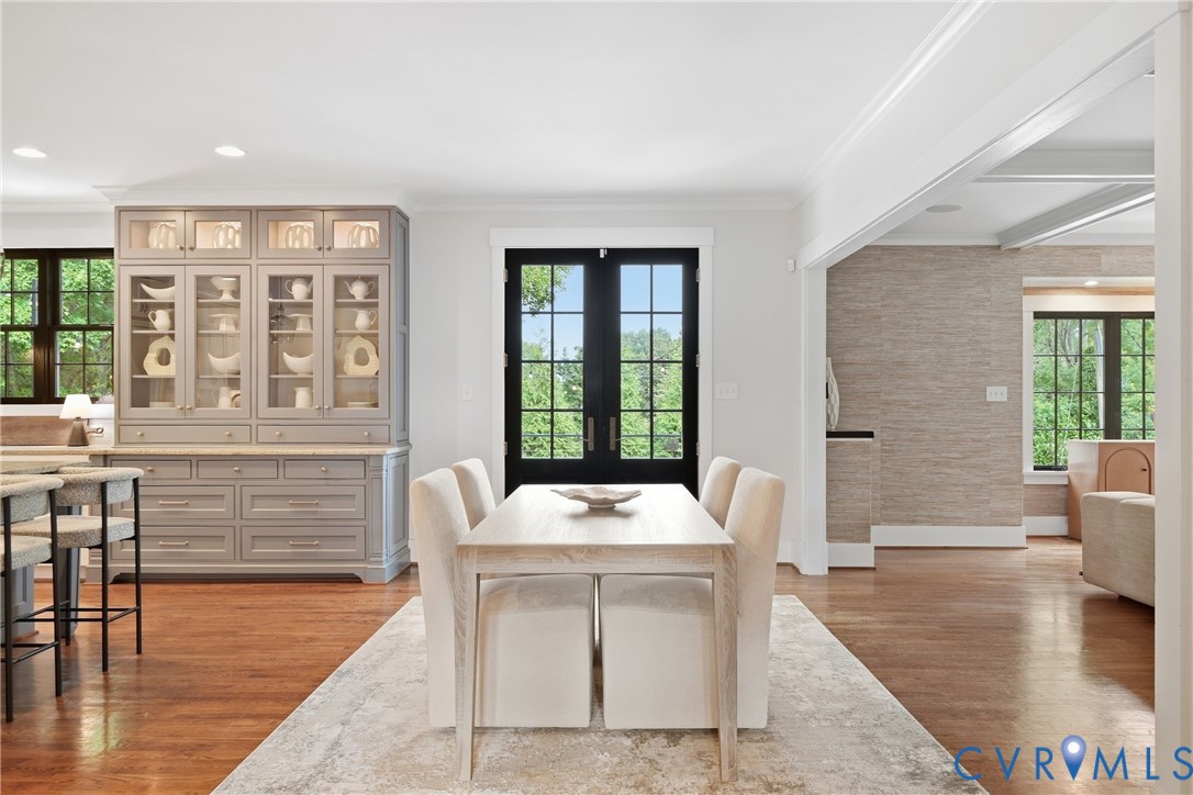 Hardwood flooring throughout, built-in cabinetry with glass display, recessed lighting, and black framed French doors