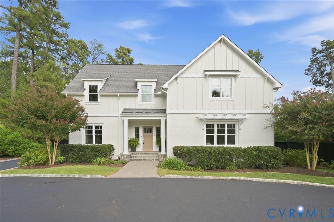 Contemporary white exterior featuring a gabled roofline, dormer windows, a covered entry, and a paved driveway