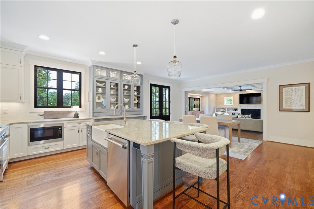 Kitchen featuring a central island with countertop seating, a farmhouse sink, and pendant lighting Kitchen featuring a central island with countertop seating, a farmhouse sink, and pendant lighting