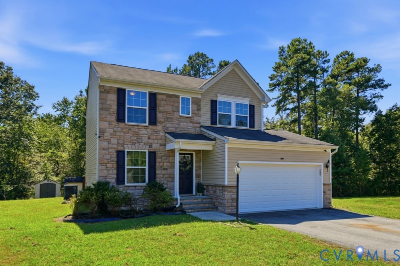 Two-story residence featuring stone and siding exterior, attached two-car garage, and a shed structure