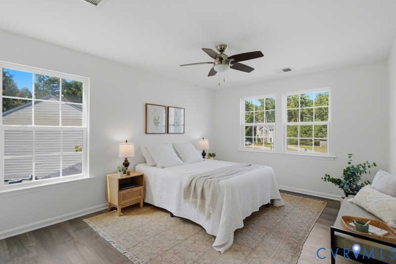 Wood-finish flooring, multiple windows, ceiling fan, and crisp white walls
