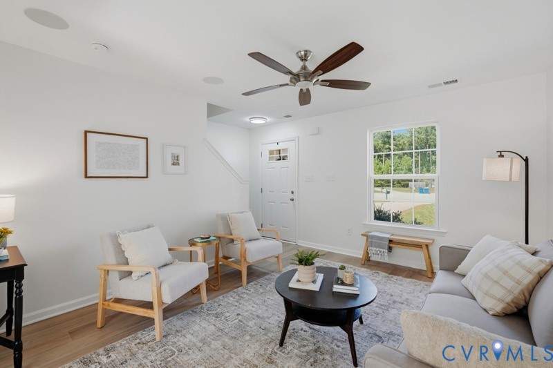 Recessed ceiling speakers, wood-finish flooring, ceiling fan, white paneled door, and white trim
