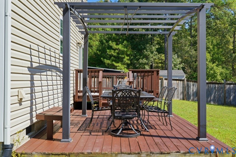 Expansive wood-finish deck featuring a built-in pergola and direct access to the exterior via a wooden staircase