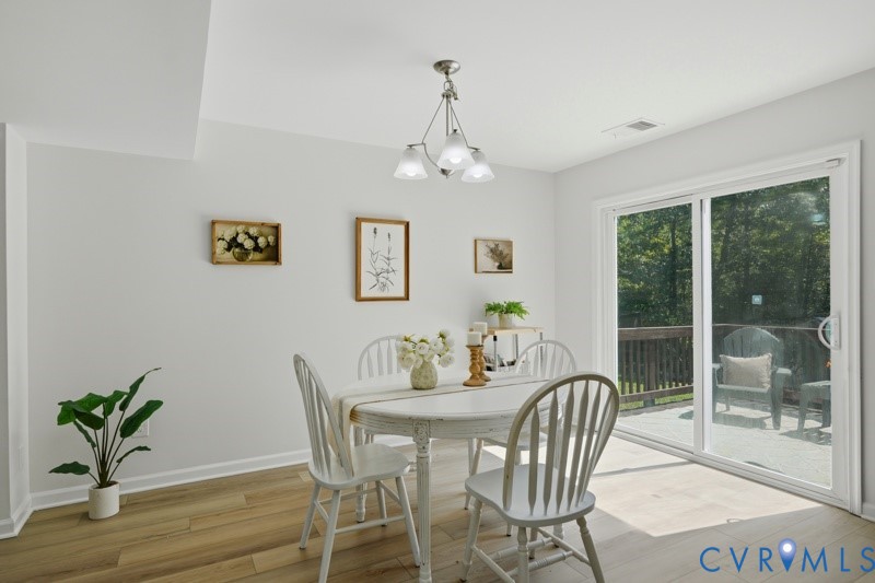 Wood-finish flooring, white walls, overhead lighting, and white sliding glass doors opening to an outdoor deck