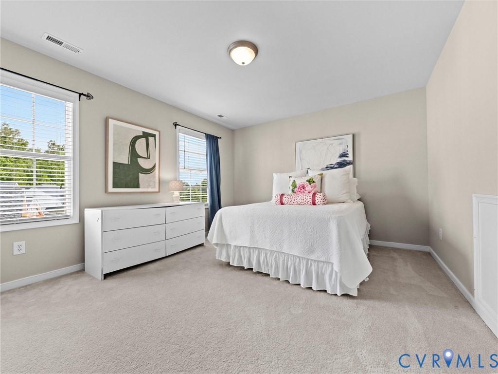 Light neutral wall paint, two windows with blinds, built-in ceiling light fixture, and plush carpeting