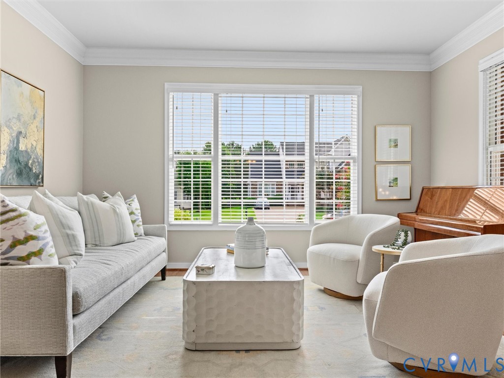 Crown molding accents a spacious interior with light-toned walls and large windows, complemented by wood-finish flooring