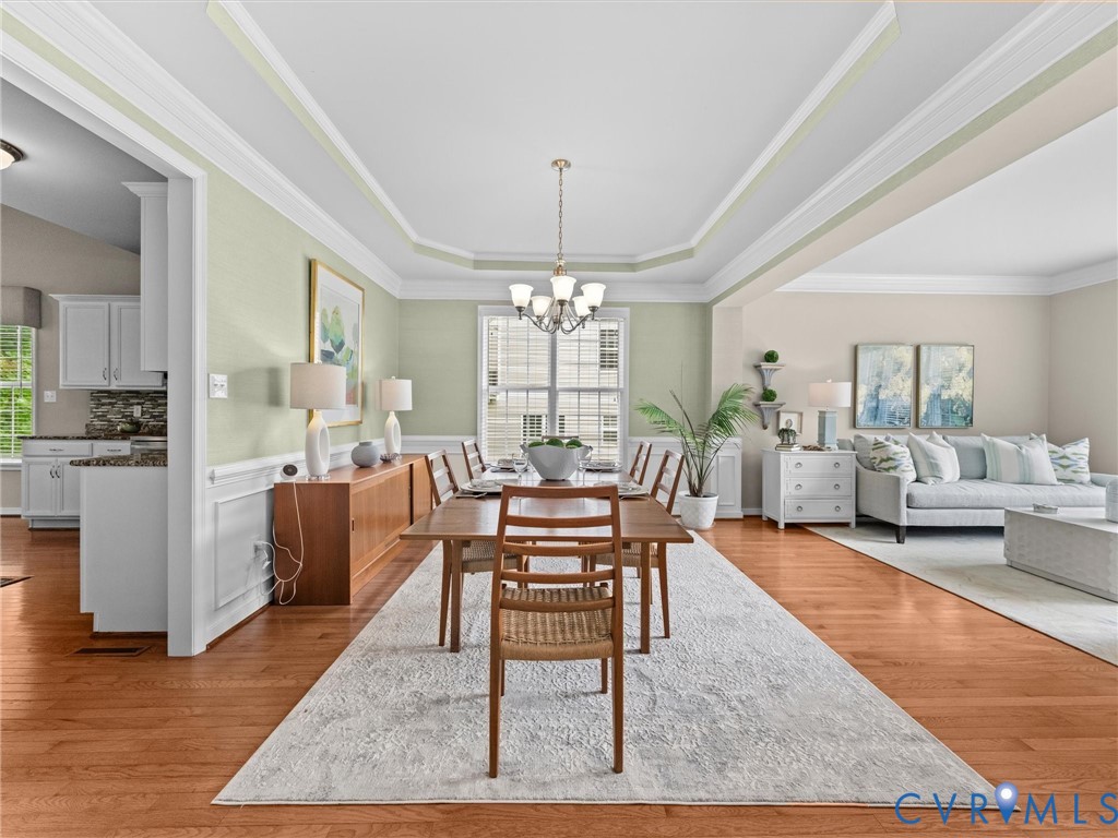 Hardwood-style flooring throughout, tray ceiling with crown molding, white chair rail molding, and a chandelier lighting fixture
