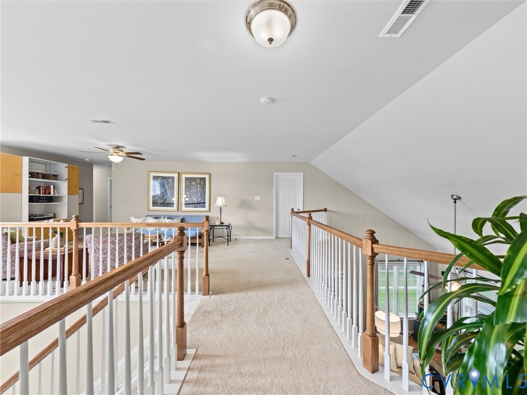 Carpeted loft area featuring a white spindle railing with wood-finish handrails, sloped ceilings, and recessed lighting