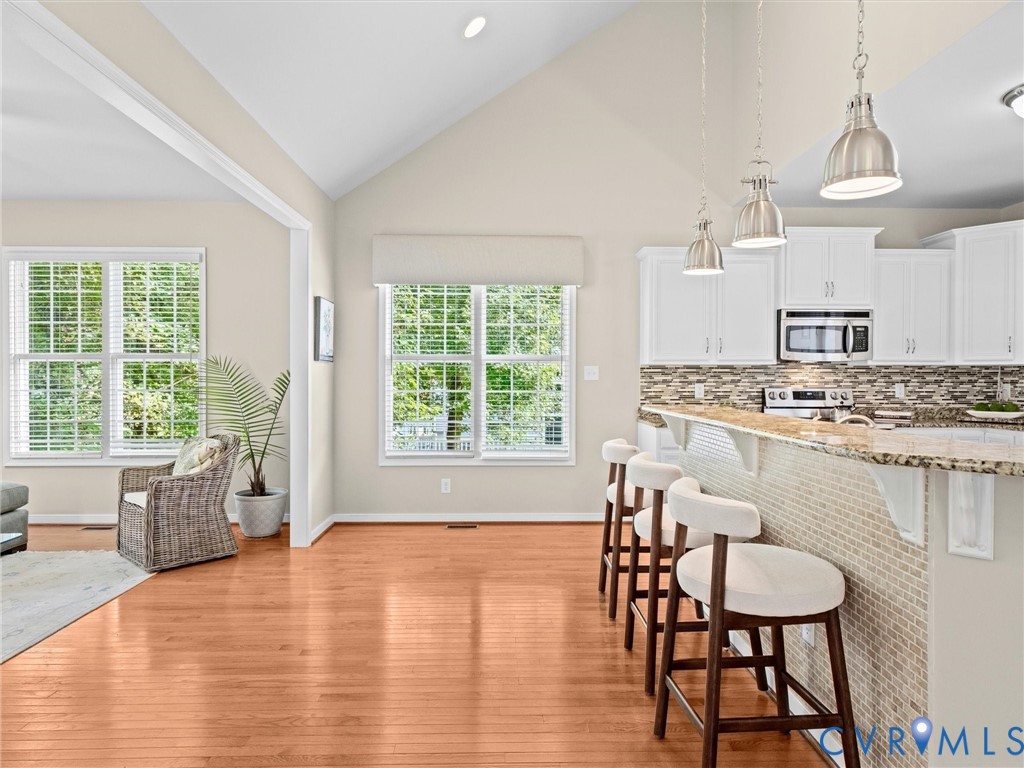 Vaulted ceiling with a recessed light, wood-finish flooring, and white trim