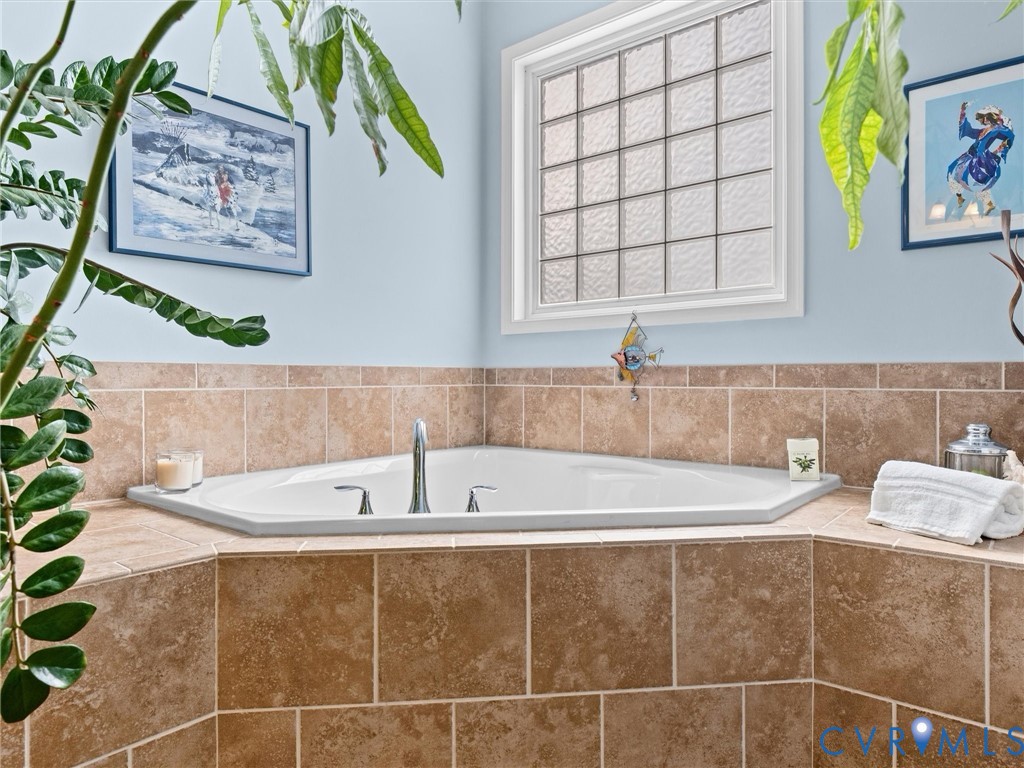 Corner soaking tub with deck-mounted chrome faucet, set into a tiled surround