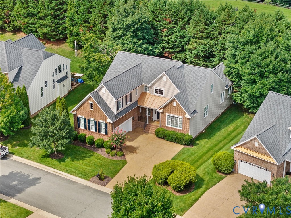 Traditional-style residence featuring a brick and siding exterior, gray shingle roof, and a prominent front-facing garage