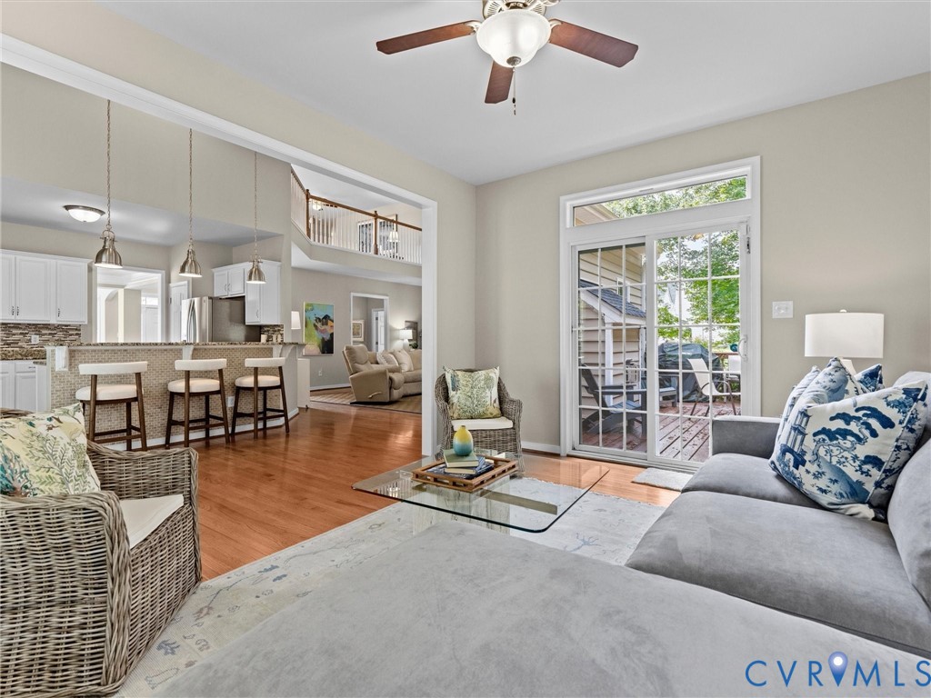 Hardwood flooring, sliding glass door with transom window, white cabinetry, stainless steel appliances, and a ceiling fan with integrated lighting