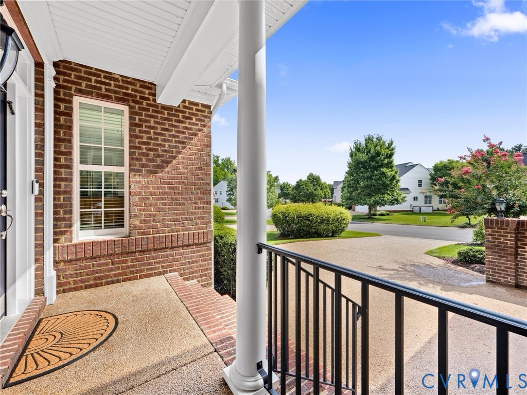 Brick exterior with white trim, covered front porch, and black metal railing