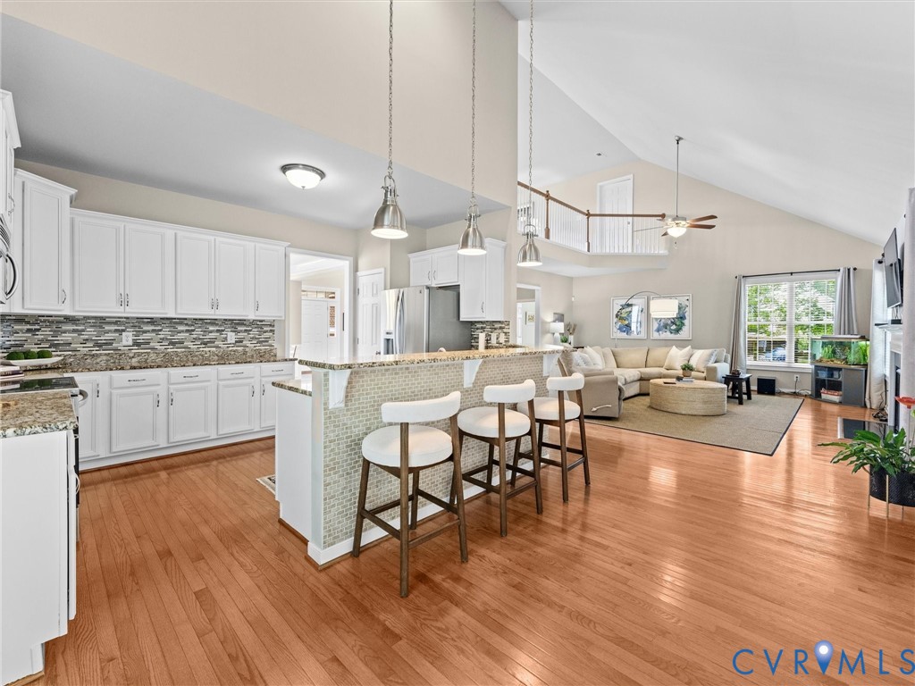 Kitchen with white cabinetry, granite countertops, and tile backsplash