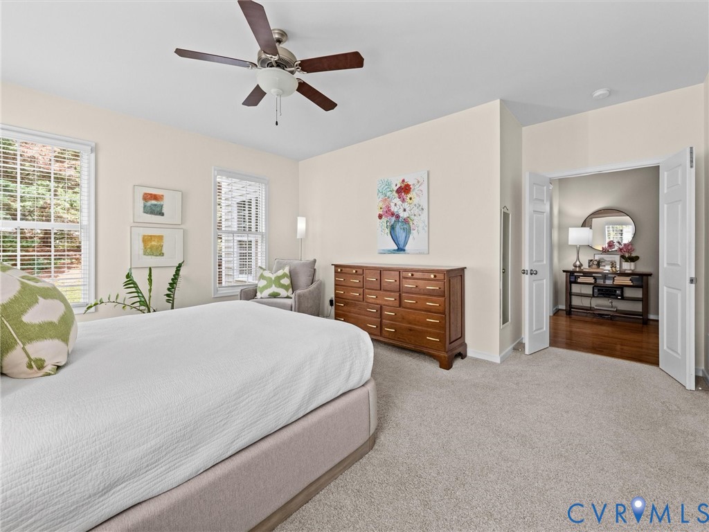 Recessed lighting, ceiling fan with wood-finish blades, two large windows with blinds, and neutral tone carpeting