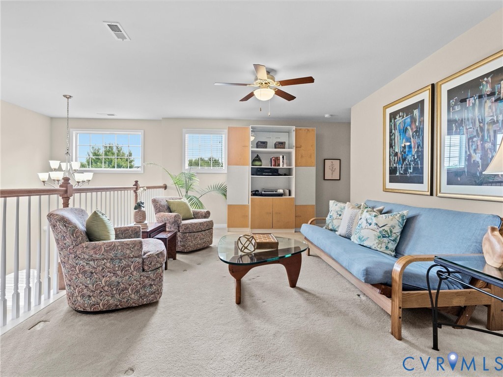 Open loft area featuring a ceiling fan, built-in shelving, white baluster railing, and natural light from multiple windows