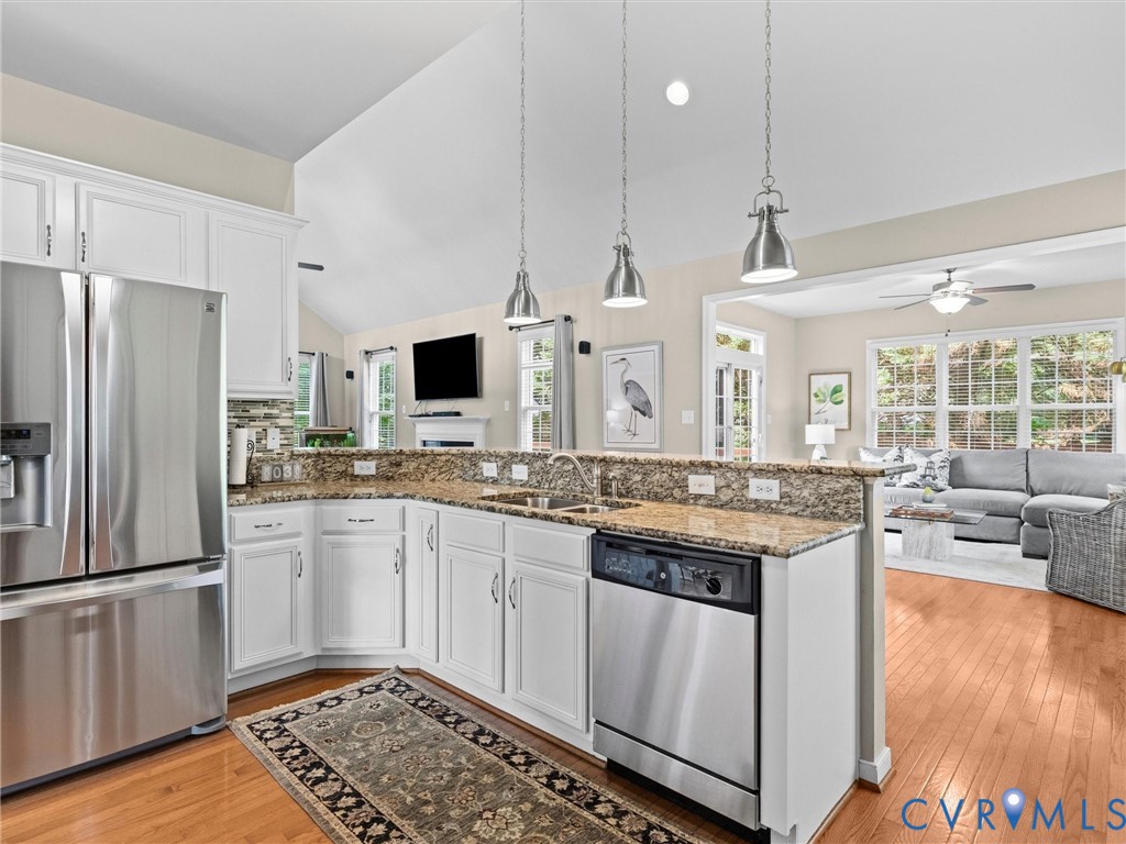 Kitchen featuring wood-finish flooring, white cabinetry, stainless steel appliances, and granite countertops