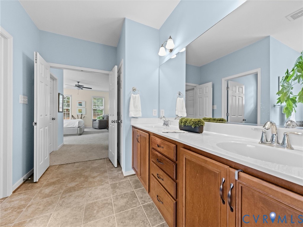 Dual vanity with integrated sinks, wood-finish cabinetry, and a large wall-mounted mirror