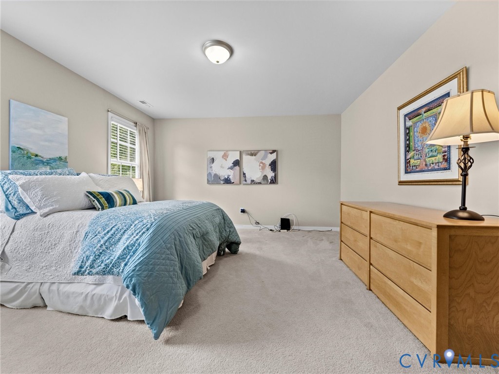 Neutral wall tones, recessed ceiling light, window with white blinds, and light-colored carpeting