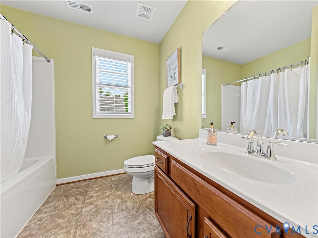 Bathroom featuring a built-in shower/tub combination, single window, vanity with an integrated sink, and wood-finish cabinetry