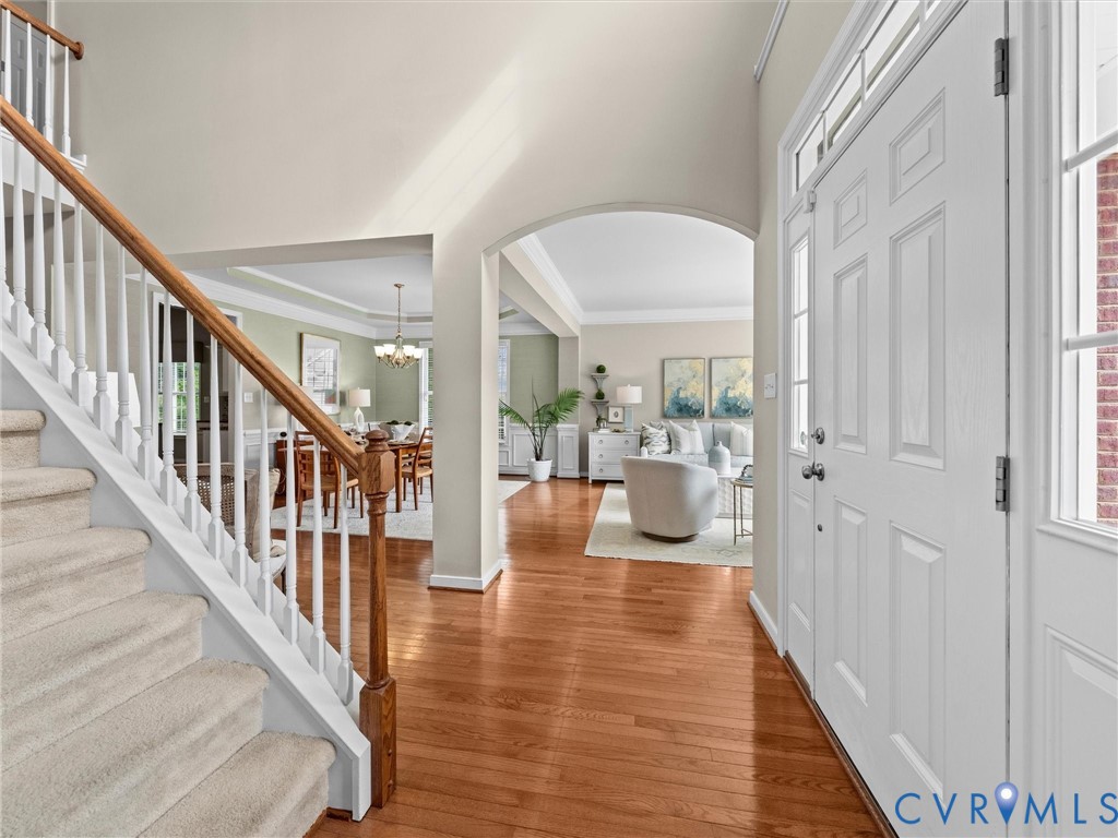 Hardwood flooring, arched doorway, paneled entry door, transom window, sidelight window