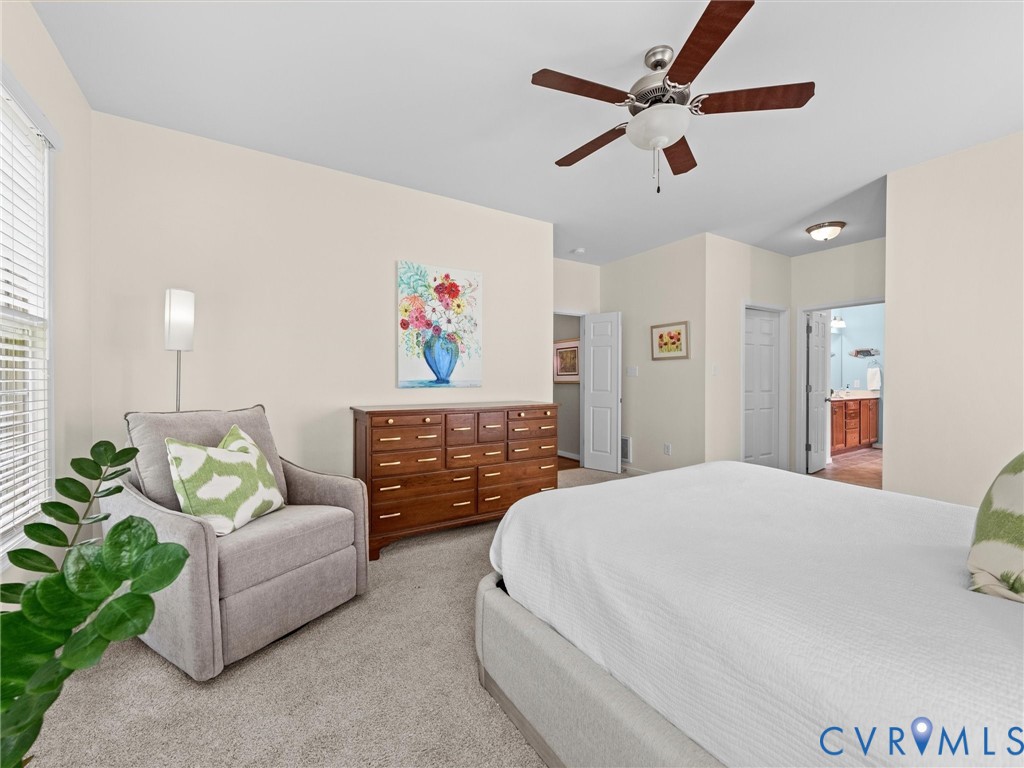Neutral tone wall paint, light-colored carpeting, a ceiling fan with integrated lighting, and multiple paneled doors