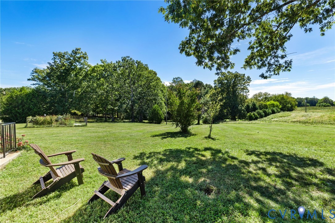 Expansive grassy lawn with surrounding mature trees and a clear blue sky