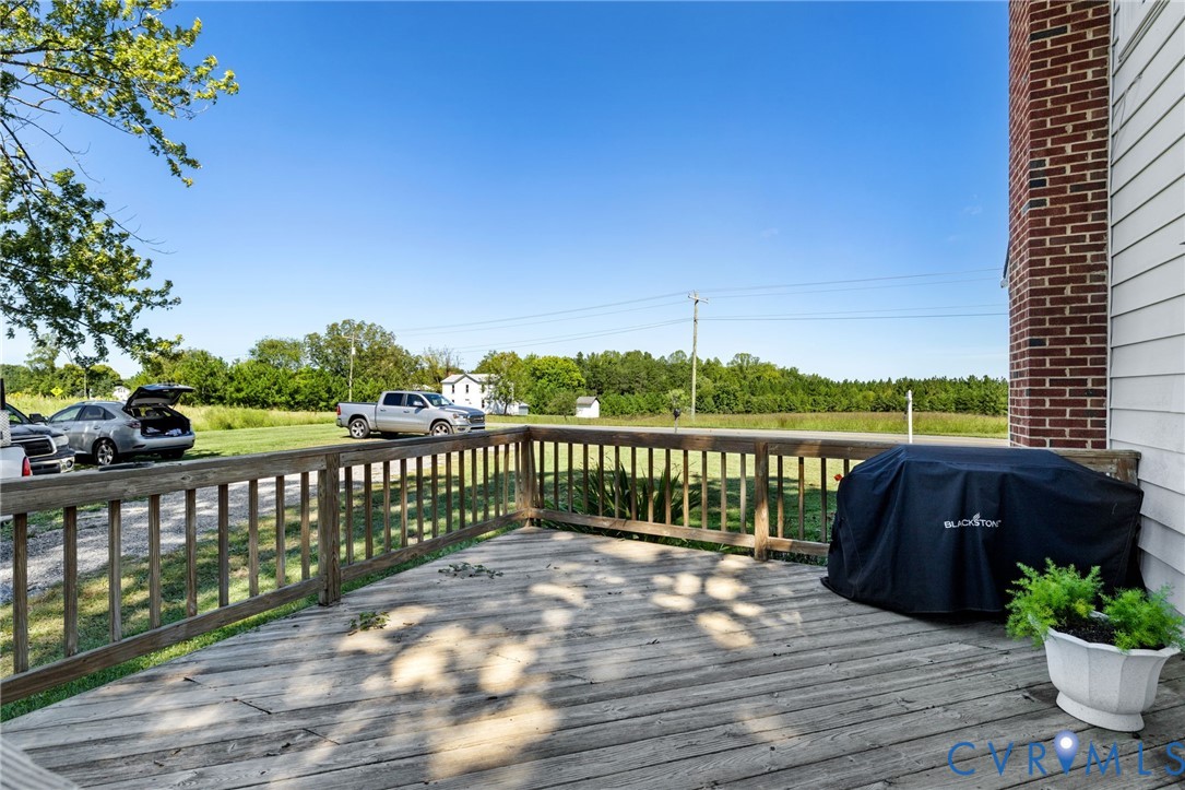 Outdoor wooden deck with railing, siding exterior, and a brick chimney structure