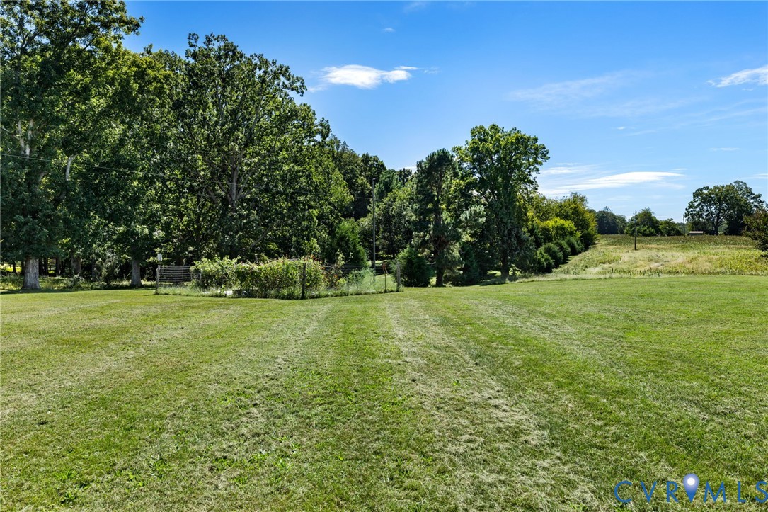 Expansive green lawn with a tree-lined border and distant fields
