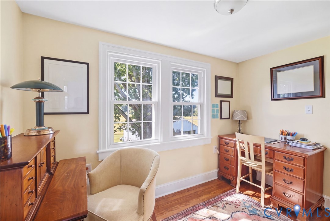 Hardwood flooring, light-toned wall finishes, and two double-hung windows with white trim