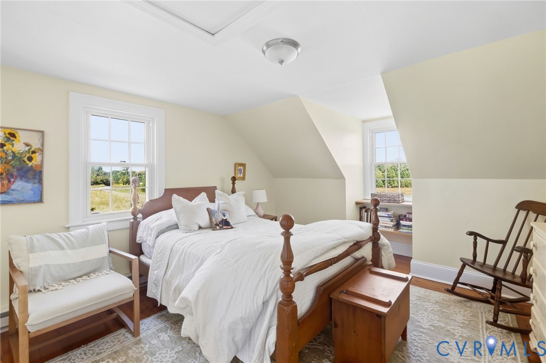Hardwood flooring, painted walls, white trim, attic access panel, and a ceiling-mounted light fixture