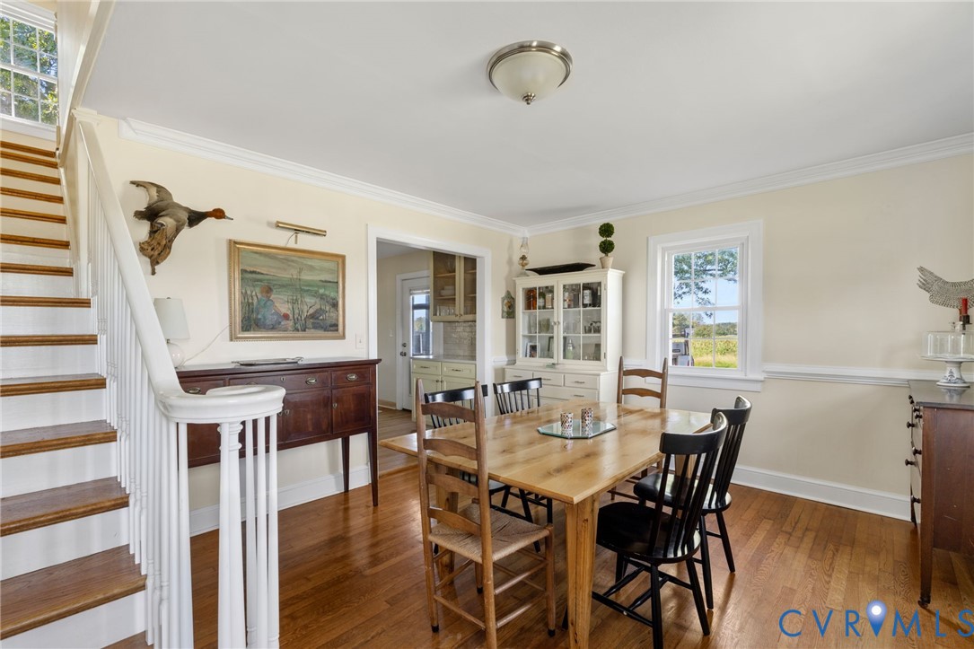 Hardwood flooring throughout, white painted staircase with wood treads, crown molding, chair rail molding, and a built-in display cabinet