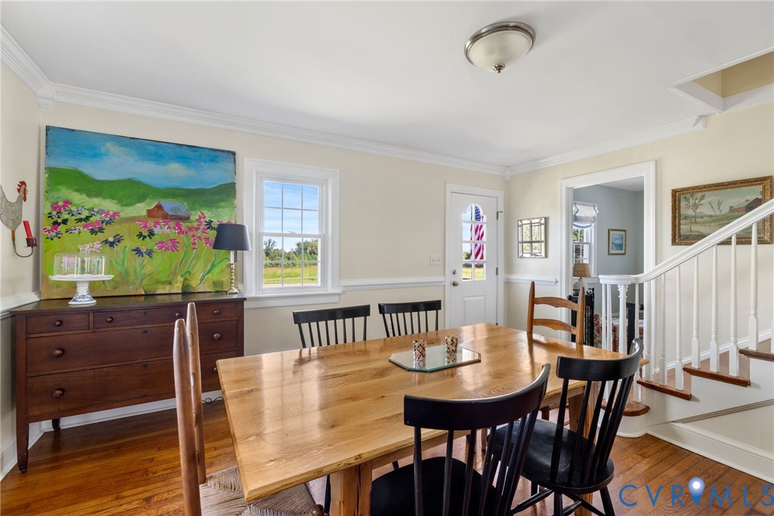 Hardwood flooring, white crown molding, a built-in staircase with white risers, and a window with natural light