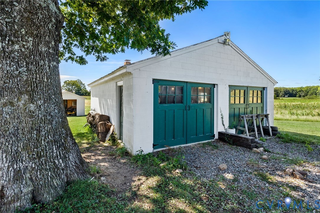 Detached white garage with two sets of green double doors and window panes