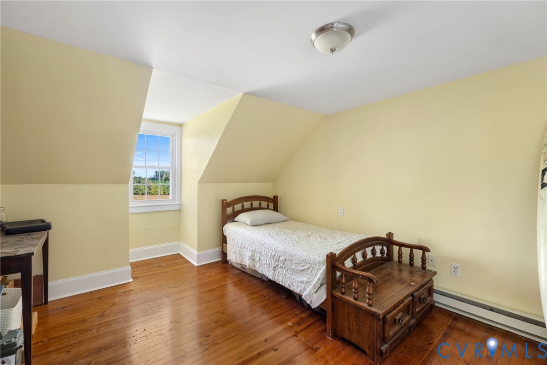 Hardwood flooring, sloped ceilings, single window with white trim, wall-mounted light fixture
