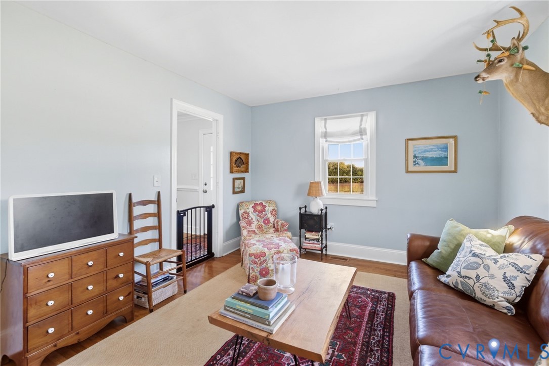 Hardwood flooring, light blue wall paint, white trim, and a window with natural light