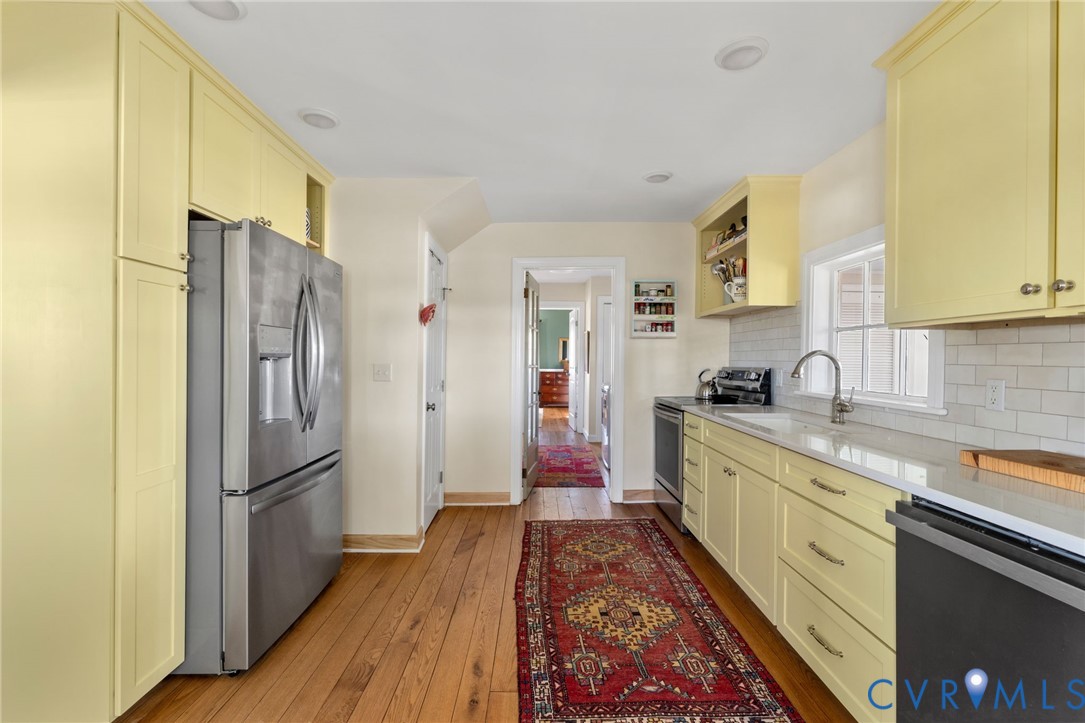 Kitchen featuring wood-finish flooring, recessed lighting, yellow cabinetry, stainless steel appliances, and a subway tile backsplash